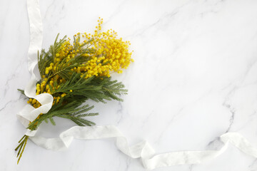 a bouquet of yellow mimosa flowers on a marble background. Concept of women's or mothers day.