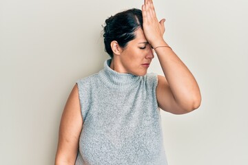 Plus size brunette woman wearing casual clothes surprised with hand on head for mistake, remember...