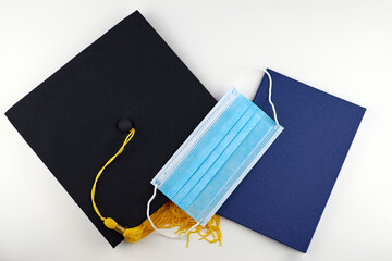Graduation cap, medical mask and diploma. Graduation rates of university and college students in the context of the coronavirus pandemic. Protection from the virus while studying.