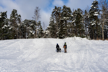 People winter sporty activity. People healthy lifestyle. Winter entertainment. Sledding and snowmobiling from high hills. Amazing beautiful snowy landscape background. Winter forest walking.