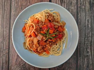 Spaghetti ground beef sauce served in a plate on wooden table.