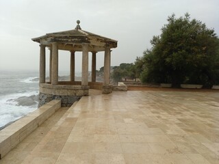 Templete, mirador con columnas enfrente del mar en S'Agaró en un día húmedo y con niebla.