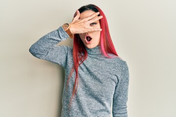 Young caucasian woman wearing casual clothes peeking in shock covering face and eyes with hand, looking through fingers with embarrassed expression.