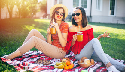 Happy smiling beautiful cute and excited best friends or sisters are having fun on the summer picnic on the cottage yard on the summer day