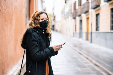Obraz premium Young blonde woman with mask talking on cell phone in the street while laughing.