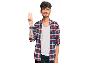 Young hispanic man wearing casual clothes showing and pointing up with fingers number three while smiling confident and happy.