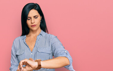 Young caucasian woman wearing casual clothes checking the time on wrist watch, relaxed and confident