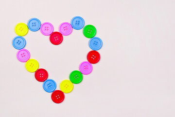 Heart shaped frame of colorful multicolor round painted wooden handmade sewing buttons isolated, close up, elevated top view