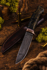 Hunting knife made of damascus steel on wooden background
