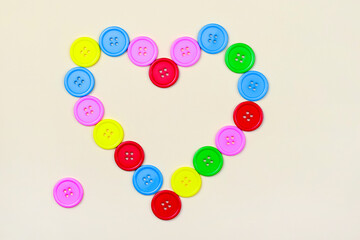 Heart shaped frame of colorful multicolor round painted wooden handmade sewing buttons isolated, close up, elevated top view