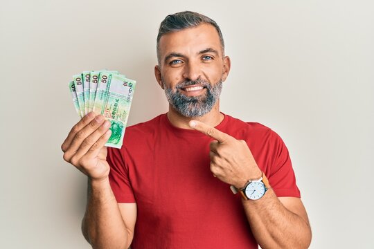 Middle age handsome man holding 50 hong kong dollars banknotes smiling happy pointing with hand and finger