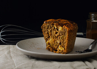 Brown apple cake on a ceramic plate with black background