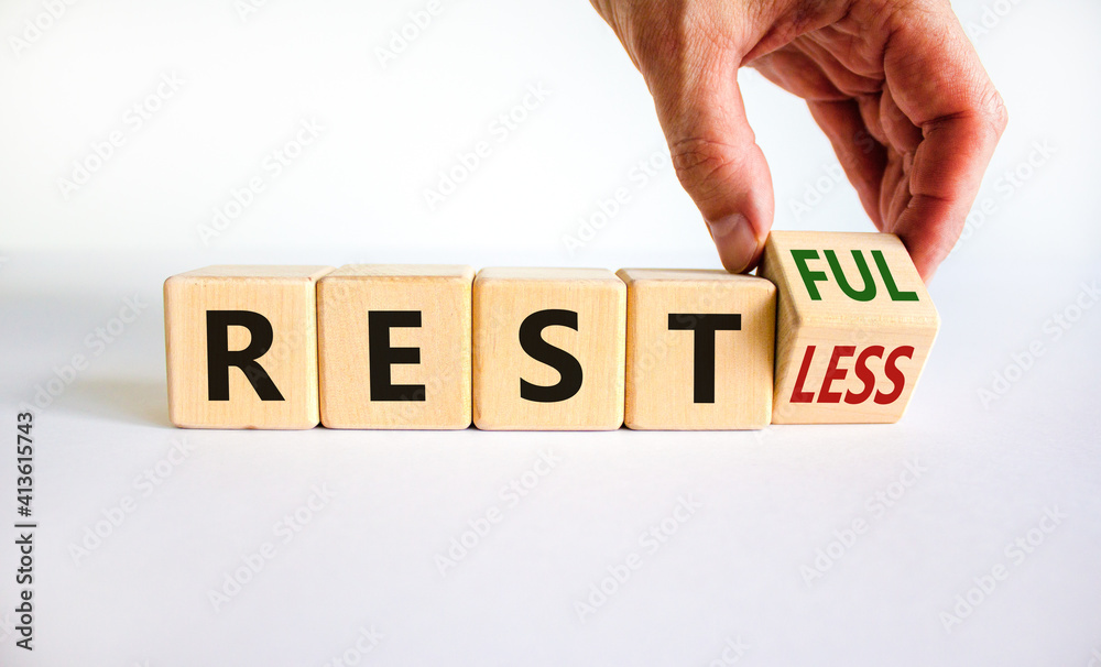 Fototapete restless or restful symbol. businessman turns the wooden cube, changes the word 'restless' to 'restf