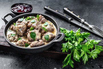 Swedish meatballs with lingonberry sauce in a frying pan. black background. Top view