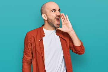 Young hispanic man wearing casual clothes shouting and screaming loud to side with hand on mouth. communication concept.