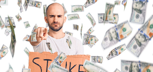 Young handsome man holding strike banner pointing with finger to the camera and to you, confident gesture looking serious