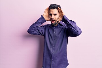 Young handsome man with beard wearing casual shirt smiling cheerful playing peek a boo with hands showing face. surprised and exited