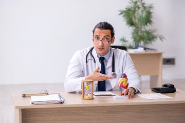 Young male doctor cardiologist in time management concept