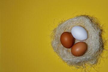 Three eggs, white on a yellow background, lay flat. Space for the text. Nest