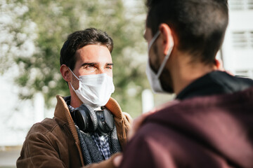 Two gay men with face masks on lovingly looking at each other while one is touching the other's face.