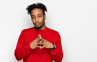 Young african american man with beard wearing casual winter sweater hands together and fingers crossed smiling relaxed and cheerful. success and optimistic