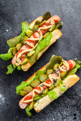 Homemade hot dogs with vegetables, lettuce and condiments. Black background. Top view