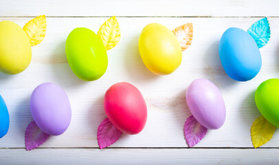 Yellow, blue, green, red, purple Easter eggs painted on a white wooden background