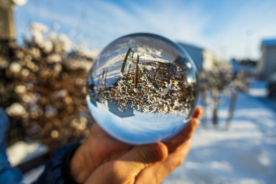Close up macro view of hand holding crystal ball with inverted  image of winter natural landscape. Sweden.