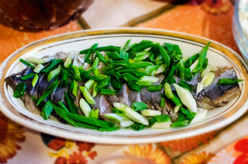 Herring fish with green onion on the plate. Tasty food.