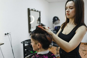 a girl hairdresser makes a hairstyle for a woman client in a modern beauty salon.