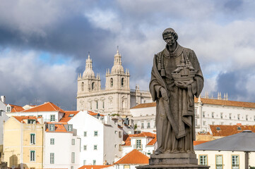Stone statue of São Vicente, patron saint of Lisbon in the viewpoint called "Sun Gates". In the background the Church or Monastery of São Vicente de Fora
