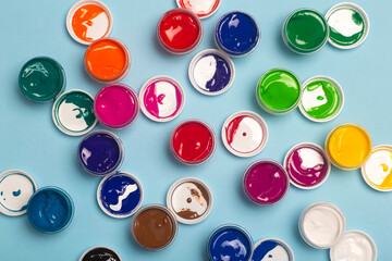 Acrylic paints of various colors for drawing are open on the table. Bright colorful background from...