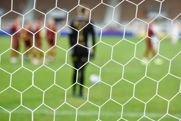 Net in the football goal with players before penalty shoot in the background.