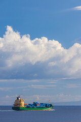 Obraz premium cargo ship nearby Capo Peloro Lighthouse in Punta del Faro on the Strait of Messina, most north eastern promontory of Sicily, Italy