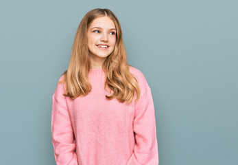 Beautiful young caucasian girl wearing casual winter sweater looking away to side with smile on face, natural expression. laughing confident.