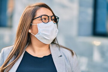 Young hispanic plus size businesswoman wearing medical mask standing at the city.