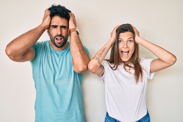 Beautiful young couple of boyfriend and girlfriend together crazy and scared with hands on head, afraid and surprised of shock with open mouth