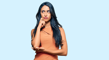 Beautiful hispanic woman wearing summer dress serious face thinking about question with hand on...