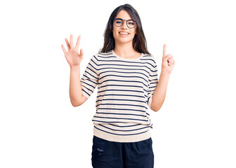 Obraz na płótnie Canvas Brunette teenager girl wearing casual clothes and glasses showing and pointing up with fingers number six while smiling confident and happy.