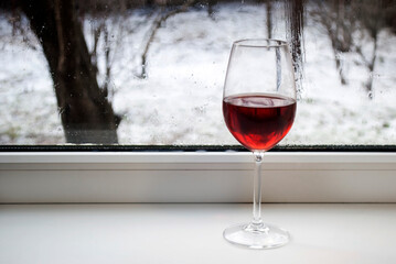 A glass of wine on the windowsill. Winter weather outside the window