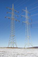 Zwei Strommasten in einer Schnee bedeckten Landschaft.