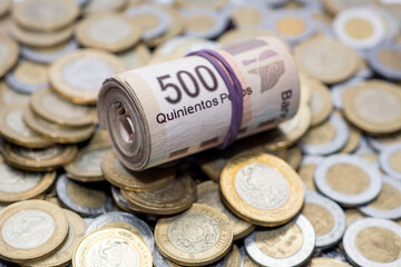 Rollo de billetes de 500 pesos mexicanos sobre monedas de diferentes denominaciones.
Roll of 500...