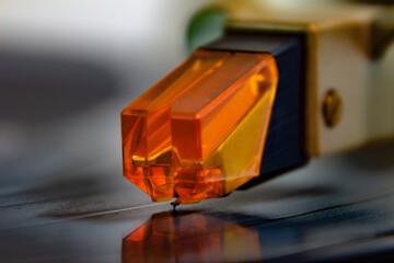 Close up of a turntable acoustic pickup with needle on a vinyl record, selective focus