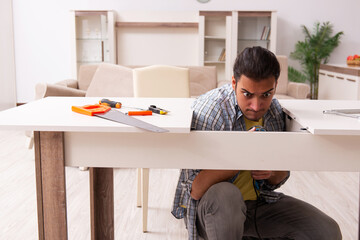 Young male carpenter repairing furniture at home