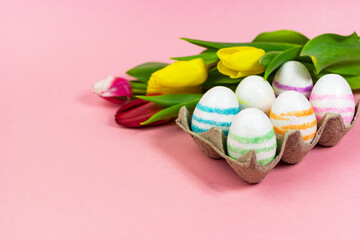 Easter painted eggs with tulips on a pink background. Copy space. Easter celebration concept.