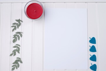 Kartka papieru biała i czerwona świeca na białym drewnianym blacie - obrazy, fototapety, plakaty