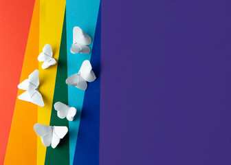 Rainbow paper background with white paper butterflies origami. Zero discrimination day concept.