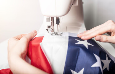 Female hands sewing american flag on sewing machine for us holiday