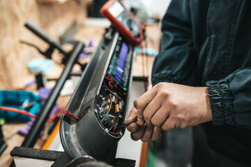 Man repairing electrical scooter in special workshop. Special workshop for repairing electrical scooters and bicycles.