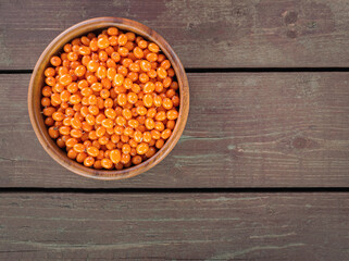 Ripe fresh sea buckthorn in wooden pot on a wooden background. Top view. Flat lay